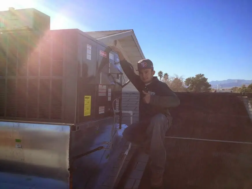HVAC technician performing Air Duct Cleaning on a rooftop unit in Derby