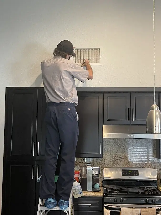 Technician inspecting an air vent during HVAC service in Derby